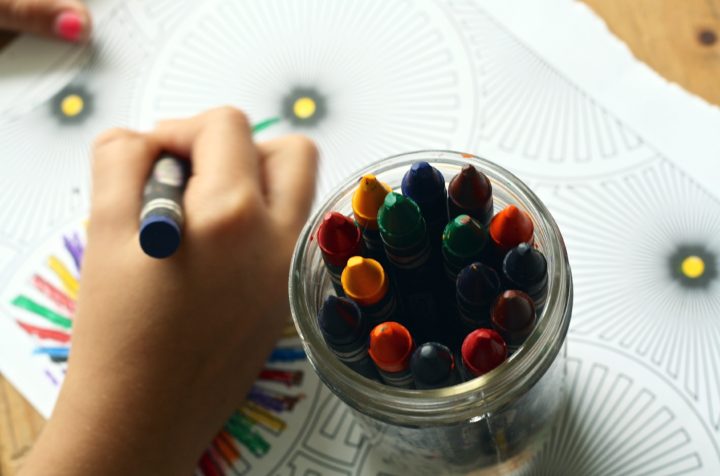 A close up image of a child coloring in a page